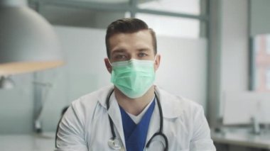 Hastane ofisinde tıbbi maske takan güvenilir otantik bir doktorun portresi. Doğrudan kameraya bak. Coronavirüs enfeksiyonunun yayılımıyla mücadele ediyoruz..