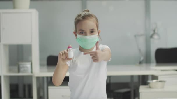 I händerna på en liten flicka, en flaska vaccin, pekar hon på det med handen, slowmotion. — Stockvideo