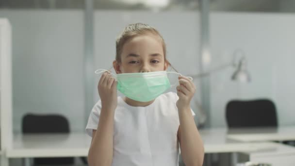 Cute baby girl removes the medical mask from her face, sighs with relief and smiles — Stock Video