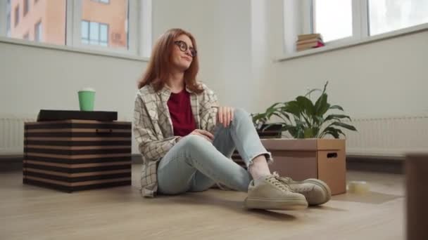 Eine Frau sitzt auf dem Boden und betrachtet ihre Sachen mit Missfallen — Stockvideo