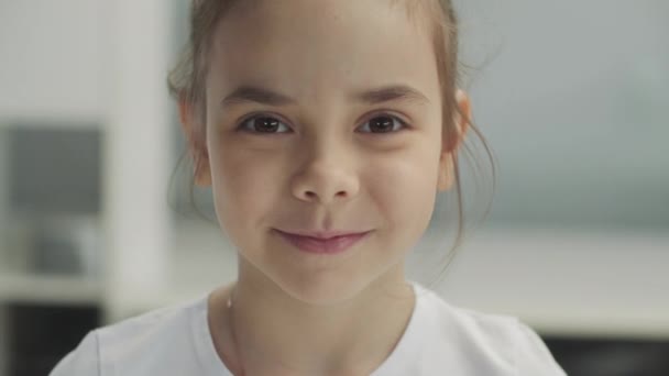 Groot portret van een klein bruin lachend meisje in een wit T-shirt — Stockvideo