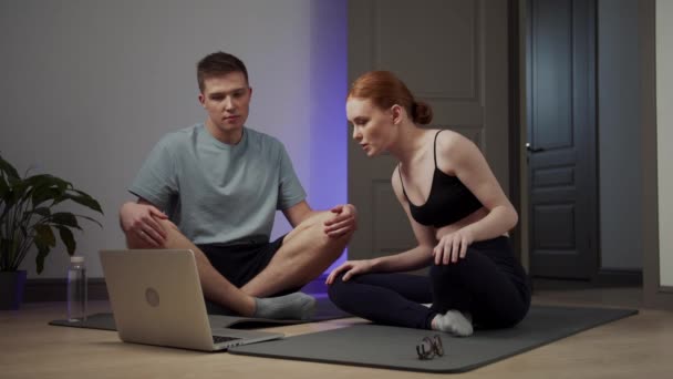 Dziewczyna i jej chłopak oglądają lekcje medytacji na laptopie i próbują się zrelaksować — Wideo stockowe