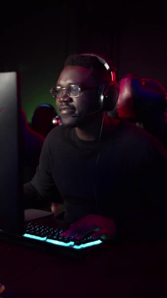 Koyu tenli bir adam bilgisayarda bilgisayar oyunu oynuyor takım arkadaşlarıyla takım konuşmasında konuşuyor. — Stok video