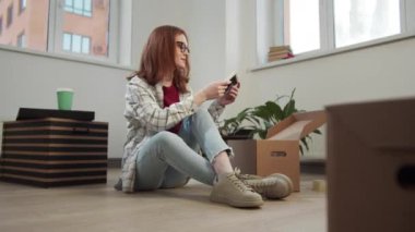 Genç bir kadın bavulunu açıyor ve yerde oturmuş fotoğraflara bakıyor.