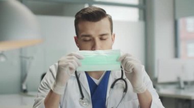 Genç, sevimli bir doktor kovid 19 hastalarını kabul etmeye hazırlanıyor. Maskesini takıyor ve yavaşça kameraya bakıyor..