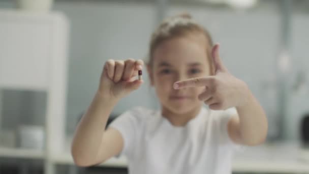 Une petite fille au labo tient une capsule de médecine et hoche la tête au ralenti. — Video