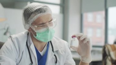 Özel bir klinikteki deneyimli bir doktorun elinde bir şişe ilaç. Koronavirüs aşısının geliştirilmesi. Yeni bir ilacın prototipi, yavaş çekim..