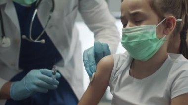 Küçük bir kıza bir doktor tarafından aşı verilir, korkar ve iğne batırıldığında korkuyla gözlerini kapatır, yavaş çekimde..