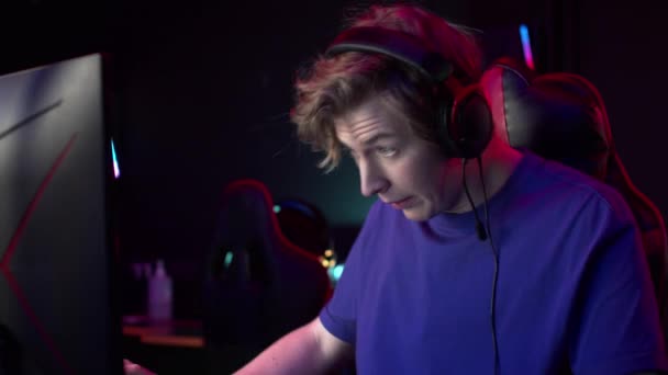 Ein netter Kerl mit Kopfhörern spielt in einem Computerclub ein Videospiel, der Administrator zeigt, dass die Zeit vorbei ist, Zeitlupe — Stockvideo