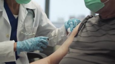 Klinikte covid-19 aşısının tanıtımı, genç bir hemşire ve yaşlı bir hasta, yakın plan.