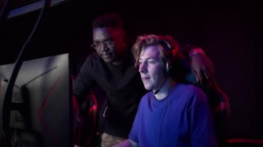 Tecrübeli bir esportçu koyu tenli arkadaşına bilgisayar kulübünde nasıl oyun oynanacağını gösterir.