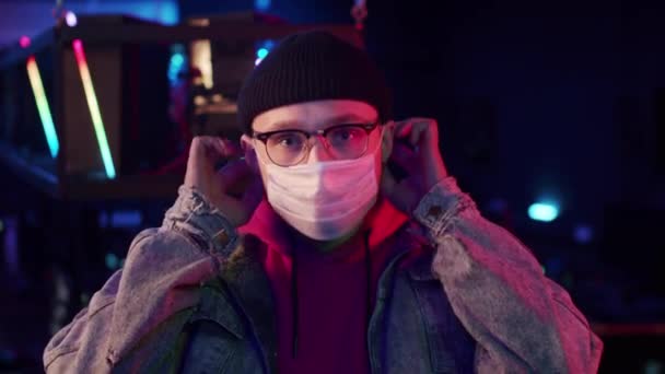 Az online videojáték-bajnokság kezdete előtt egy szemüveges és kötött sapkás játékos orvosi maszkot tett az arcára, hogy megvédje a koronavírustól. — Stock videók