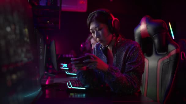 The chinese gamer girl decided to take a break and play on her smartphone, she is tired, losing and upset — Stock Video