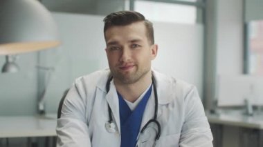 Ofisindeki çekici bir erkek doktor steteskopu yavaş çekimde boynuna yerleştiriyor.