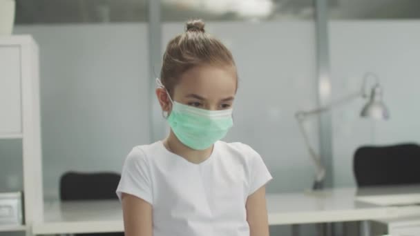 In the doctors office a child girl with a medical mask coughs — Stock Video