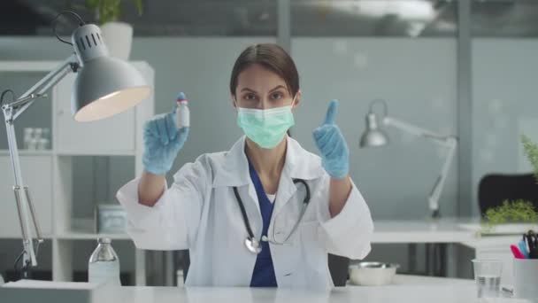 Zkušený lékař žena v kanceláři ukazuje láhev léku ukazuje, že je to dobré, ona doporučuje — Stock video