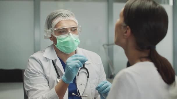 Un medico in abito medico e guanti fa uno striscio per l'analisi PCR in un giovane paziente. Un test per rilevare il coronavirus. Indagine sulla popolazione di massa. — Video Stock