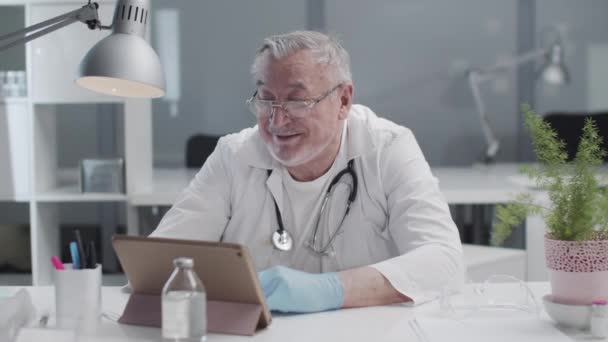믿을 만 한 남성 의사가 자신의 비디오 블로그에서 태블릿으로 생방송을 이끌고 있다. 온라인 의학. 비디오 전화 상담. — 비디오