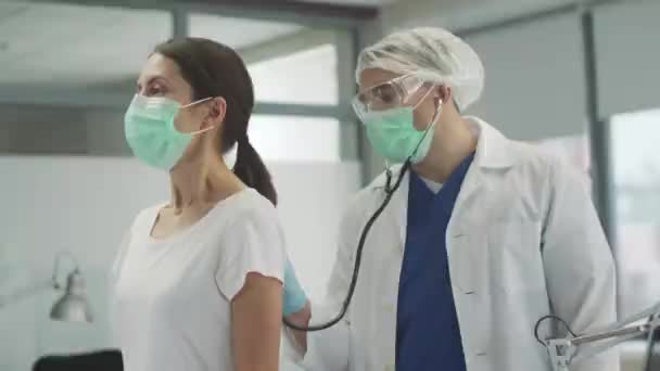 Опытный терапевт слушает легкие своего пациента женщины с симптомами коронавируса — стоковое видео