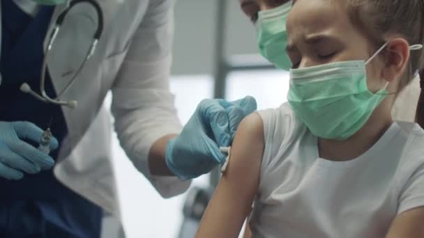 Una niña bonita tiene mucho miedo de la vacunación, cierra los ojos y se encoge de miedo — Vídeo de stock