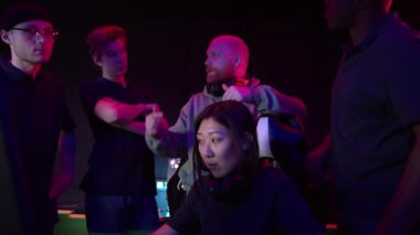 Eskport koçu Asyalı bir kızın maçını izliyor ve ekibe ne yapmaları gerektiğini anlatıyor, ağır çekim.