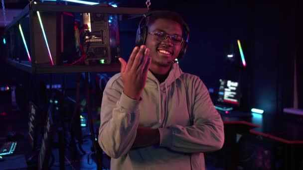 En söt afrikansk-amerikansk spelare i glasögon och hörlurar lockar med handen att ansluta sig till honom — Stockvideo