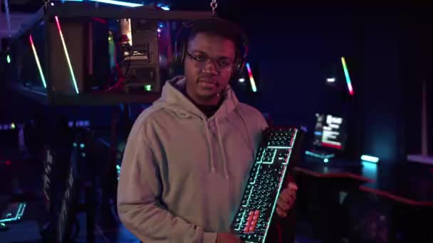 Before the online gaming tournament in the computer room, an african-american gamer received a new keyboard, looks at it and likes it — Stock Video