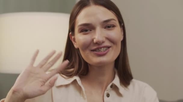 Weiße Frau winkt in die Kamera, lächelt und redet — Stockvideo