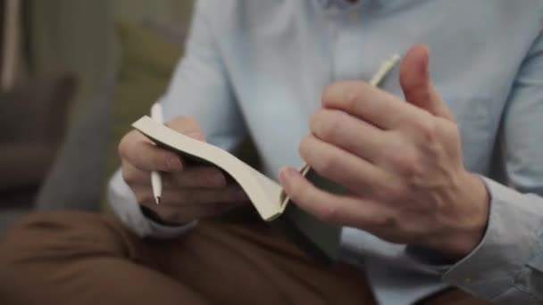 Um homem europeu sério escreve algo num caderno. — Vídeo de Stock
