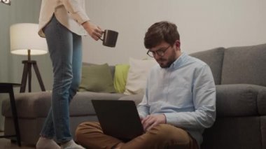 Bir kadın, çalışan bir adama bir fincan çay getirdi..