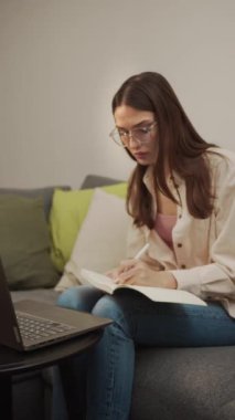 Online video dersine katılan bir kadın oturuyor ve yazıyor.