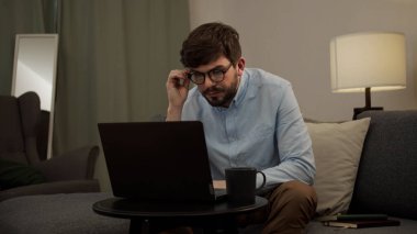 Yorgun bir adam dizüstü bilgisayarına bakar ve bir şeyler yazar..