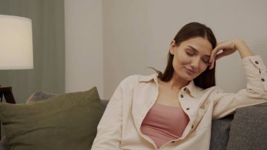 Yorgun kız gözlüklerini çıkarır masaya koyar ve kanepeye yaslanır.