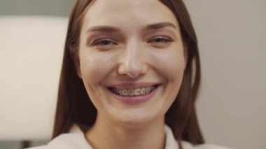 Diş teli takan beyaz güzel kadın kameraya bakıp gülümsüyor.