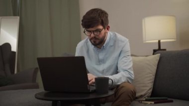 Yorgun bir adam dizüstü bilgisayarına bakar ve bir şeyler yazar..