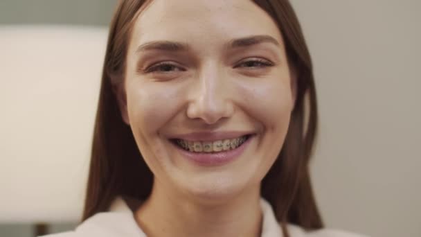 White beautiful woman with braces looks and smiles at the camera — Stock Video