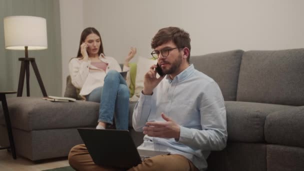 Біла європейська пара сперечається, розмовляючи по телефону в кімнаті. — стокове відео