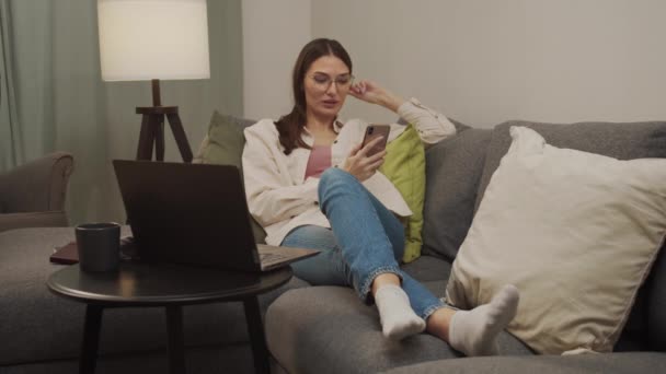 Bella donna sdraiata sul divano, a riposare e parlare al telefono. — Video Stock