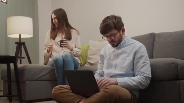 Дівчина сідає поруч з людиною з комп'ютером, і вона дивиться на iPad . — стокове відео