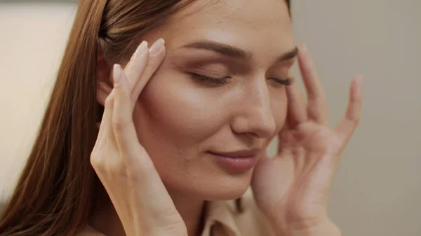 Yorgun, güzel bir kadın gözlerini kaçırıyor gözlüğünü çıkarıyor ve şakaklarına masaj yapıyor.