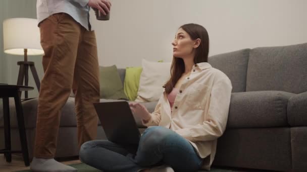 Un uomo porta il caffè per una ragazza seduta sul pavimento. — Video Stock