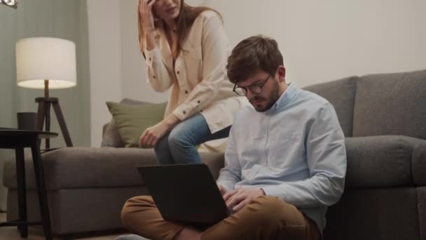 Dziewczyna siedzi obok faceta, a facet pokazuje jej coś w laptopie.. — Wideo stockowe