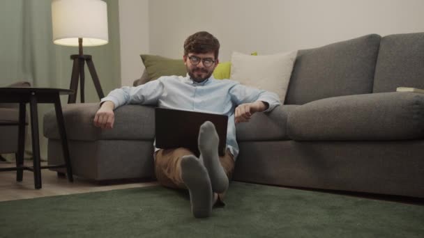 Biały człowiek komunikuje się przez łącze wideo siedząc na podłodze — Wideo stockowe