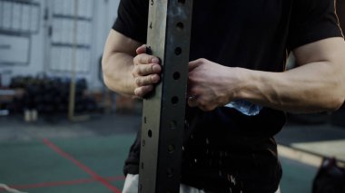 Güçlü bir sporcu su şişesini açmaya çalışıyor.