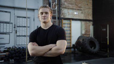 Güçlü bir atlet kollarını kavuşturup kameraya bakıyor.