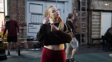 Güçlü bir atletik kız yüzünü maskesiyle çıkarıyor ve kameraya bakıyor.