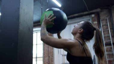 Güçlü bir atletik kadın topu atıyor ve çömeliyor.