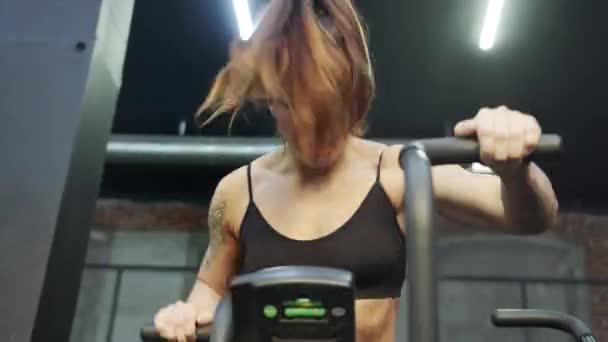 En stark idrottskvinna tränar hårt på en träningscykel — Stockvideo