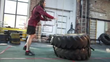 Atletik bir adam iki spor lastiği patlatıyor.