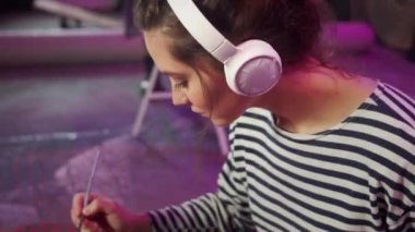 Bir sanatçı müzik çiziyor ve dinliyor. 